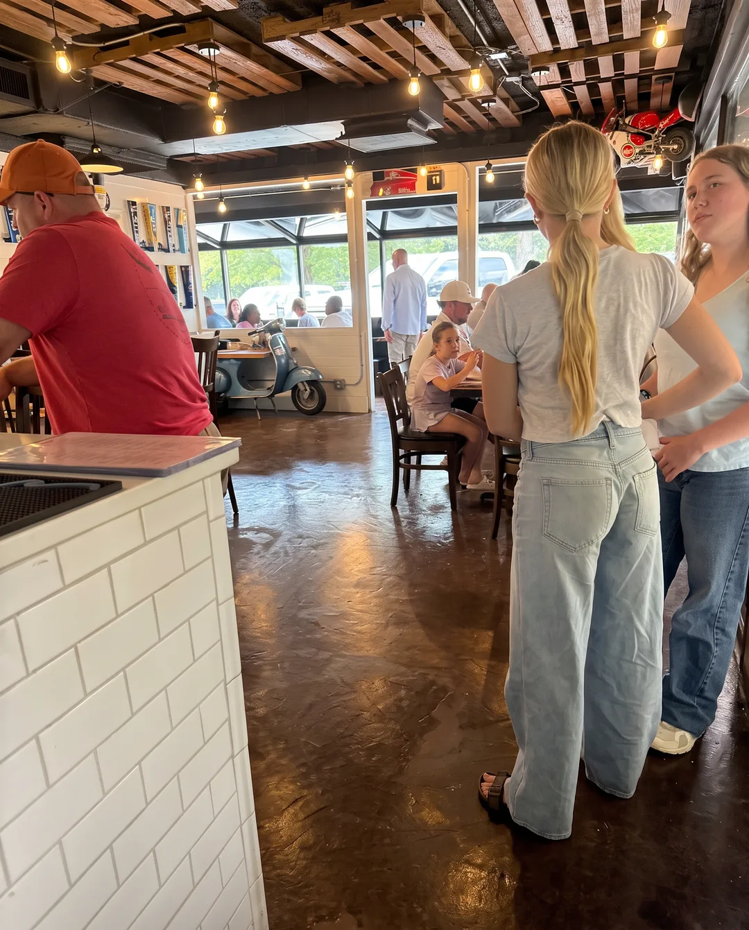 Guests at wood tables in the dining room under the slatted timber ceiling