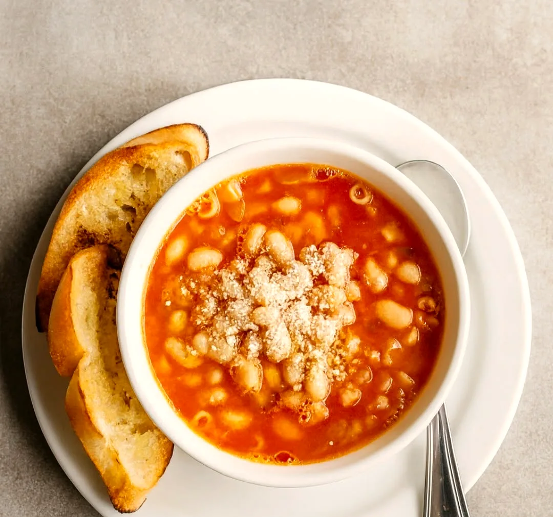 A bowl of bean soup with grilled bread on the side