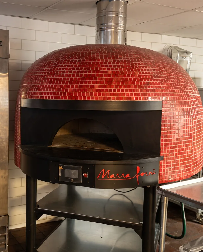 The red tiled dome of the wood-fired oven, mouth open, in the La Scuderia kitchen