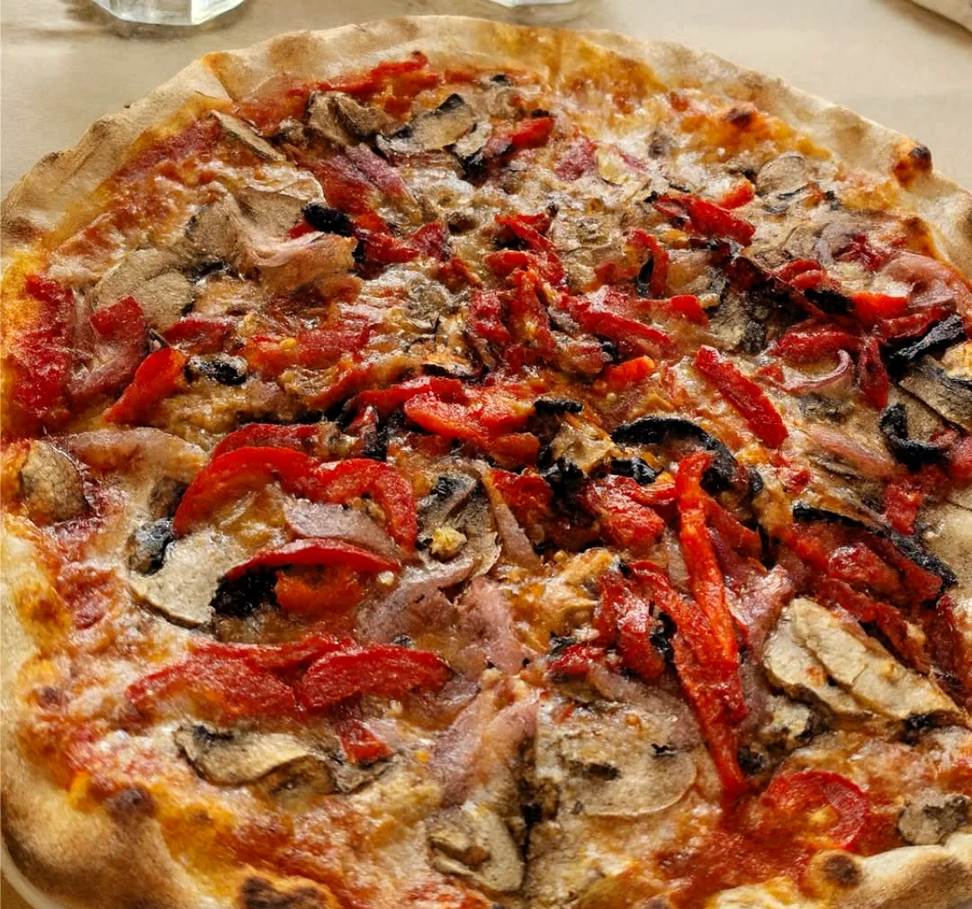 A pizza topped with roasted red peppers, mushrooms and prosciutto