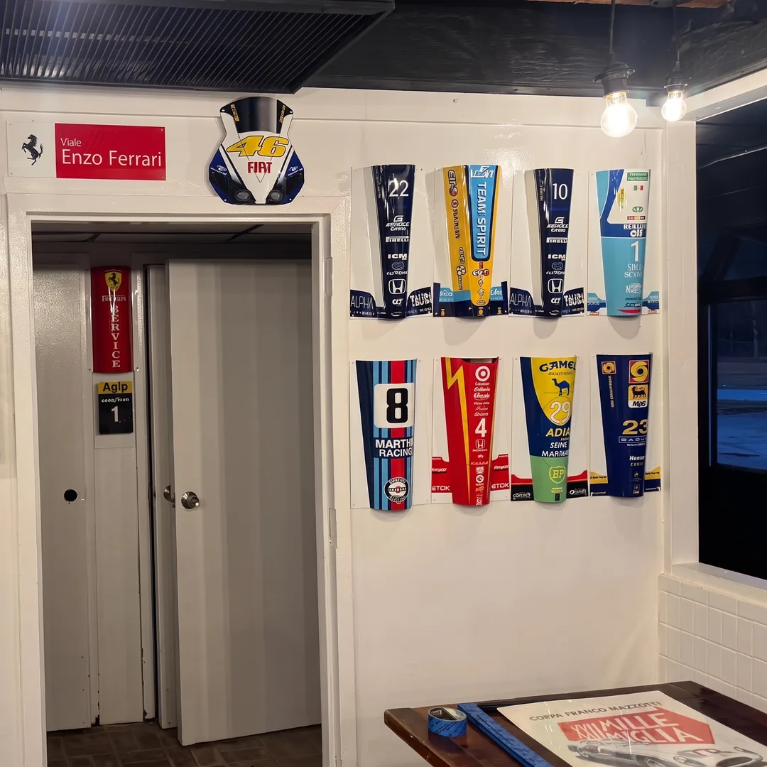 Racing pit banners and a Viale Enzo Ferrari street sign on the wall by the dining room doorway